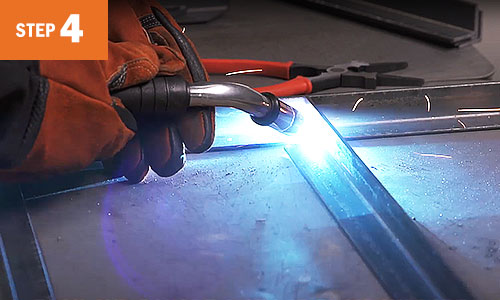 Close-up image of MIG welding on a table beam.