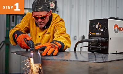 welder cutting metal with a plasma cutter