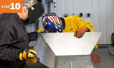 Two welders holding sheets of metal together