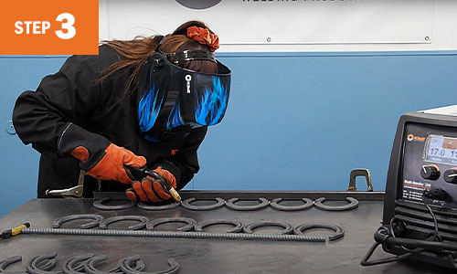 Operator welds a line of horseshoes.