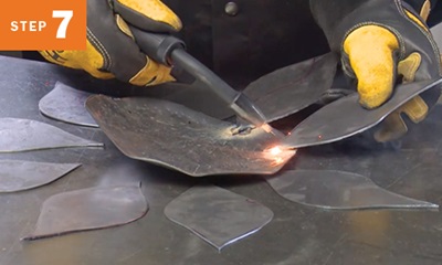 MIG welding metal pieces for a sunflower yard art project