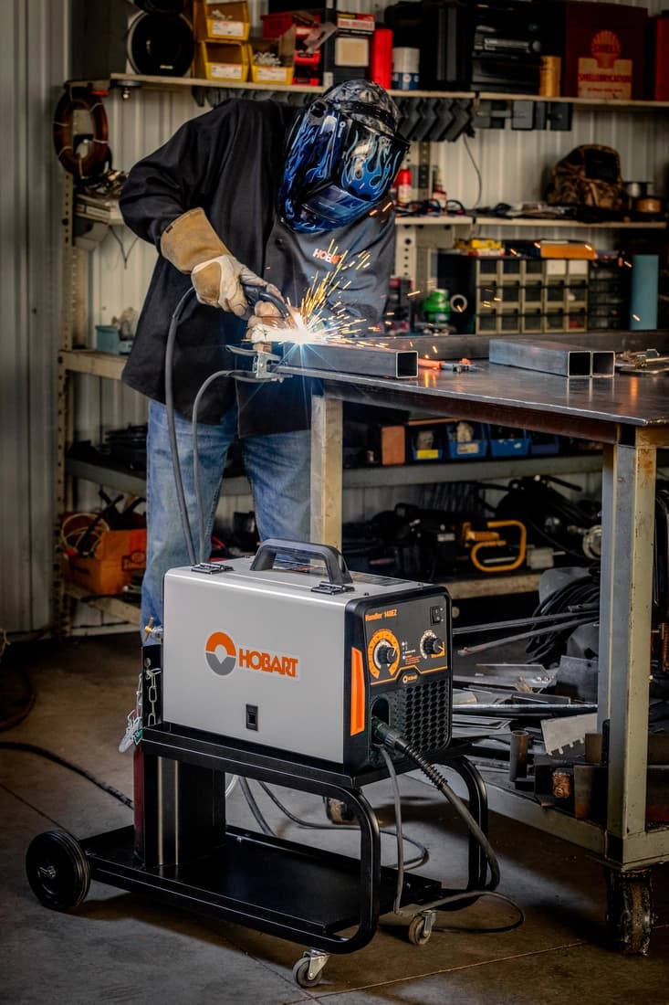 Welder in a shop welding using a Hobart Handler 140EZ MIG welding machine