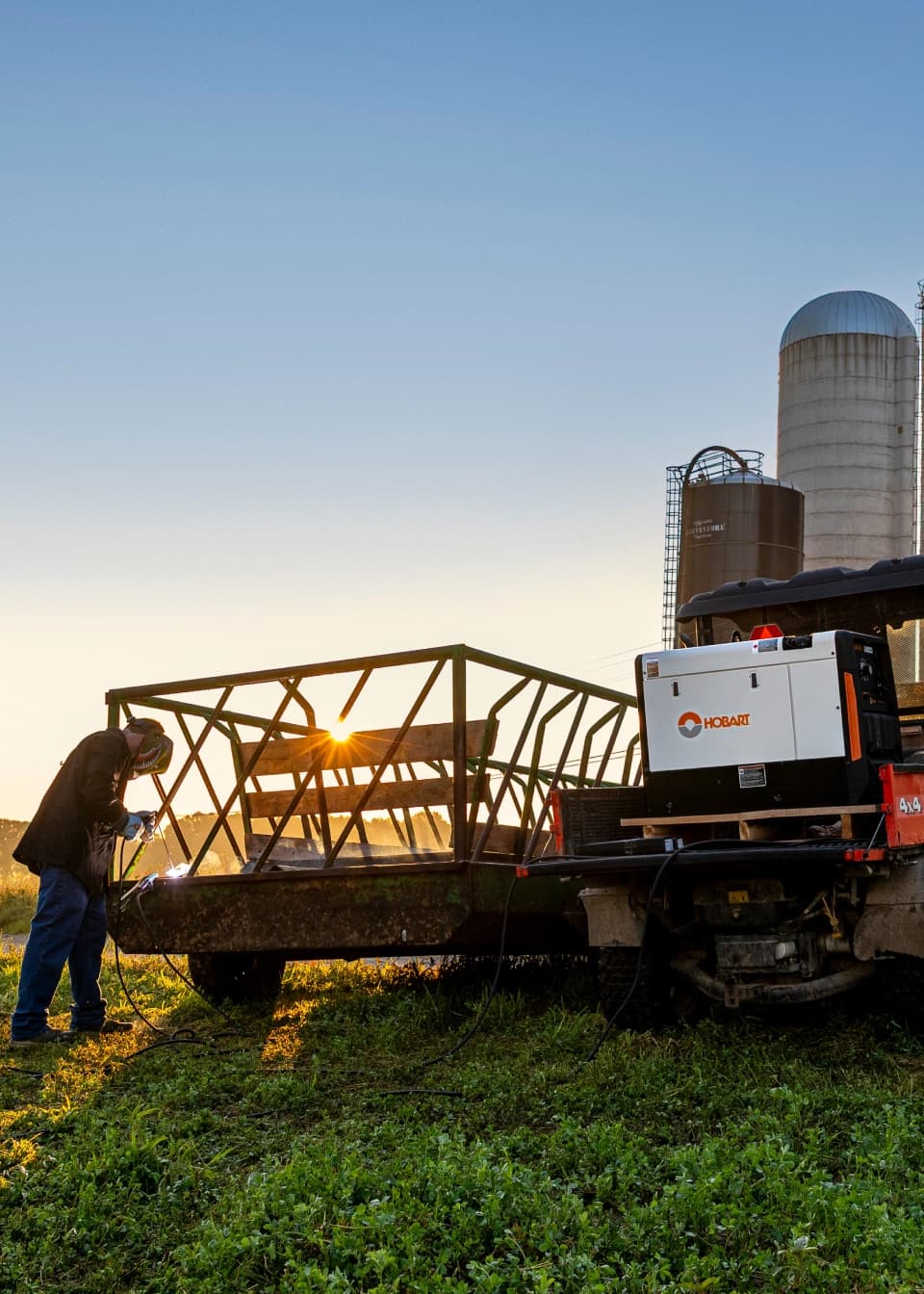 An operator using a Hobart welder on a metal trailer